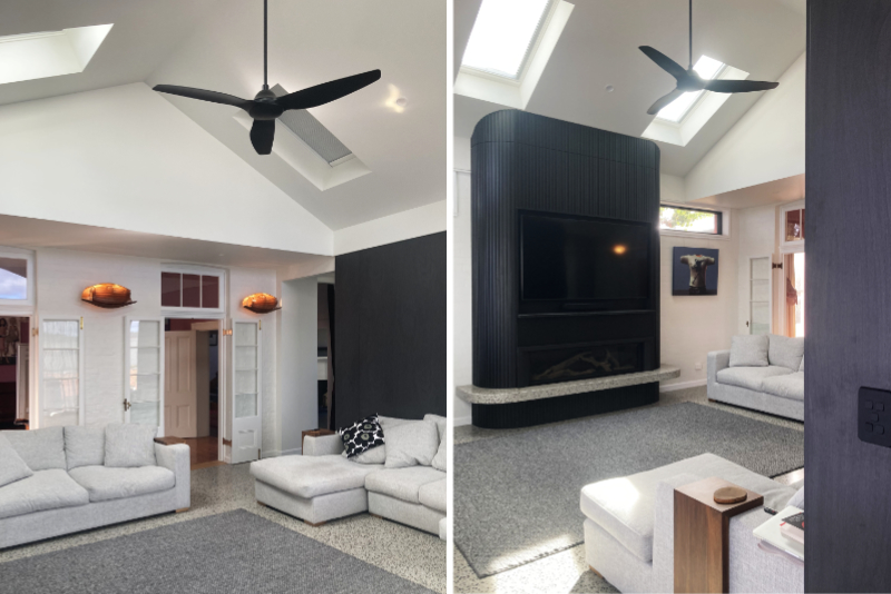 black and white living room with high raked gable ceiling, skylights, ceiling fan, black fireplace surround with curved corners
